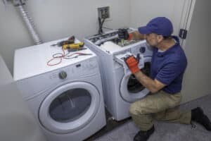 Appliance technician working on a front load washing machine in a laundry room